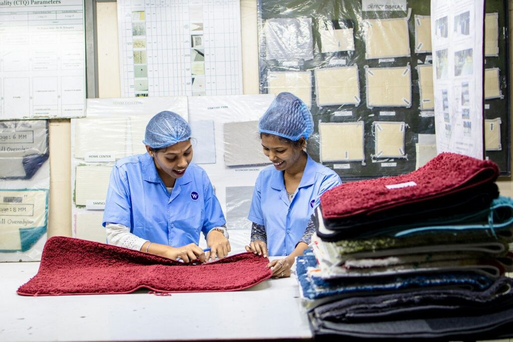 Two women are working with carpets in a factory.