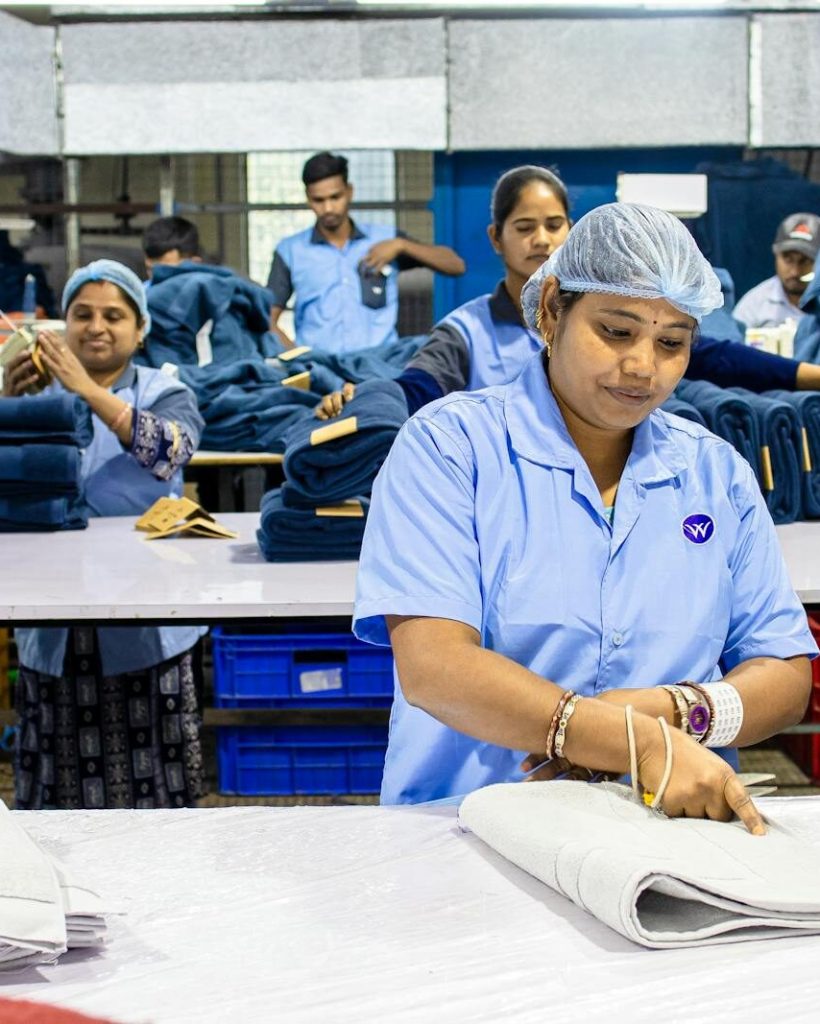 Workers in a textile factory sorting and organizing materials for production. Busy industrial setting.