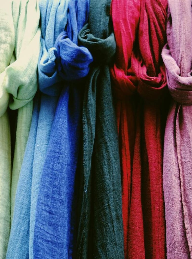 A vibrant collection of multicolored scarves displayed in a market setting.