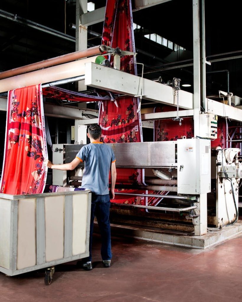 Worker operates machinery in a textile factory, overseeing fabric production.